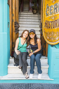 Two female friends sitting at the entrance of house in buenos aires