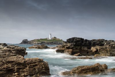 Rock formation by sea against sky