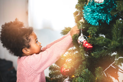 Cute girl decorating christmas tree at home