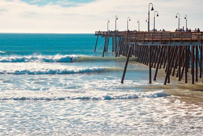 Wooden posts on beach against sky