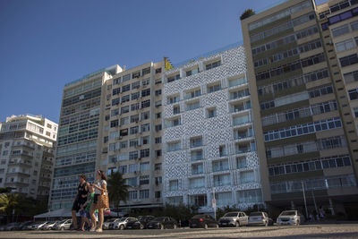 People on modern building against sky in city