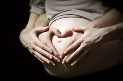 Midsection of woman touching finger against black background