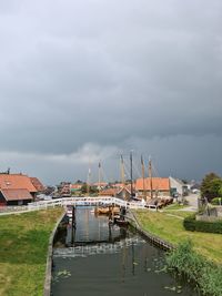 Boats moored in canal by buildings against sky