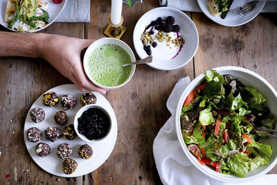 Cropped hand of man having matcha tea during meal at table