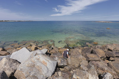 Man standing amidst rocks against sea at beach