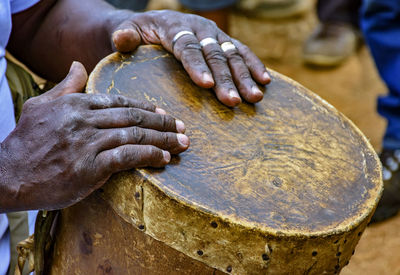 Cropped hands playing old drum outdoors