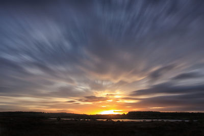 Scenic view of dramatic sky over landscape during sunset