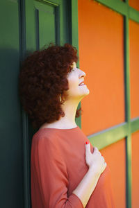 Woman in red dress leaning on a green door