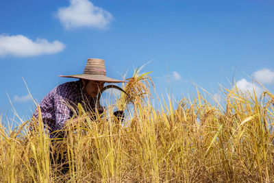 Man standing by plants on field against sky