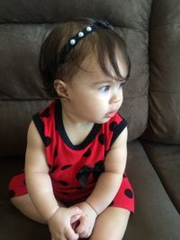 Cute baby girl sitting on sofa at home