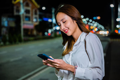 Young woman using mobile phone at night