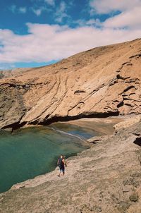 Rear view of man walking by sea and mountains