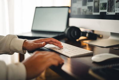 Cropped hands of man using laptop on table