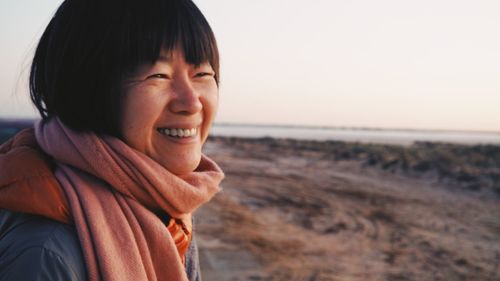 Smiling woman looking away against lake and sky