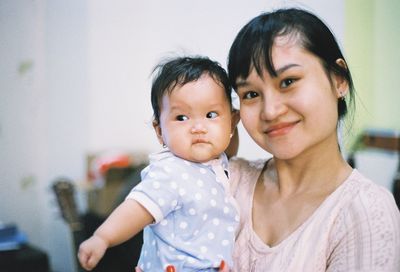 Portrait of smiling mother with baby girl at home