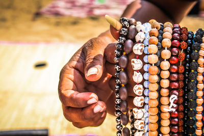 Cropped hands of man selling bead necklaces at beach