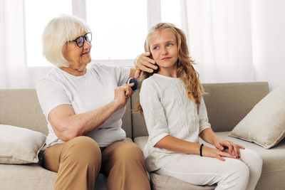 Young woman using phone while sitting on sofa at home