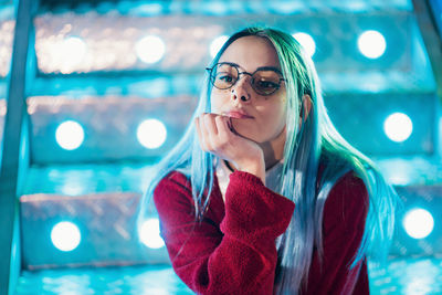 Thoughtful young woman sitting against illuminated steps