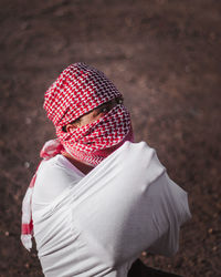 High angle portrait of man wearing headscarf kneeling on land