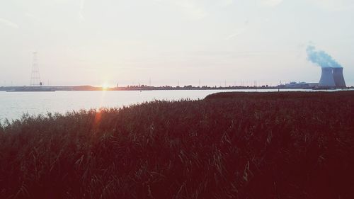 Smoke emitting from river against sky during sunset