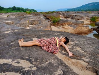 Full length of young woman relaxing on rock