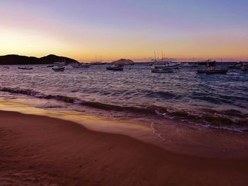 Boats in sea against clear sky at sunset