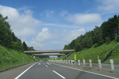 Road by trees against sky