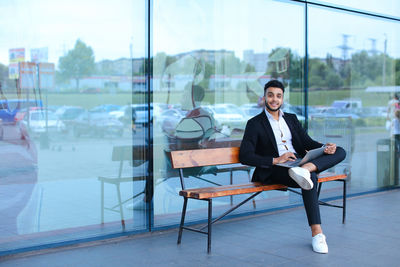 Businessman using digital tablet while sitting on bench outdoors