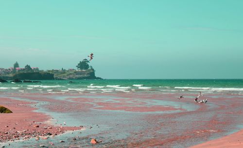 Scenic view of sea by cliff against clear sky