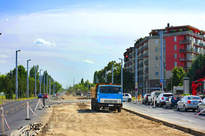 Road construction by buildings in city against sky