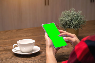 Woman using mobile phone while sitting on table