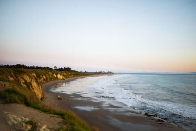 Scenic view of beach against clear sky during sunset