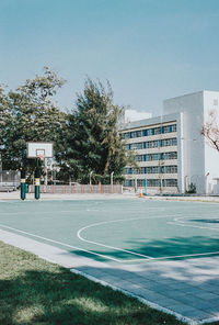 View of basketball court by buildings against sky