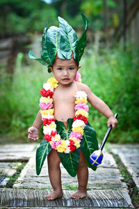 Portrait of cute boy wearing leaves standing outdoors