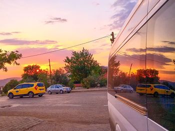 Cars on street against sky at sunset