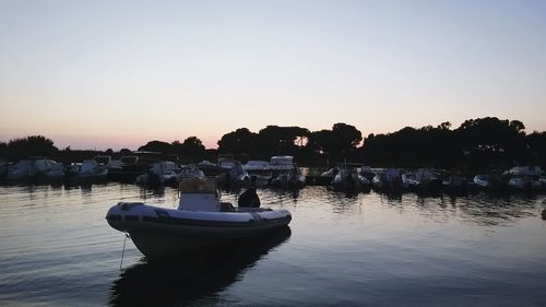 Boats moored in lake against clear sky during sunset