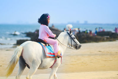 Woman riding horse on beach