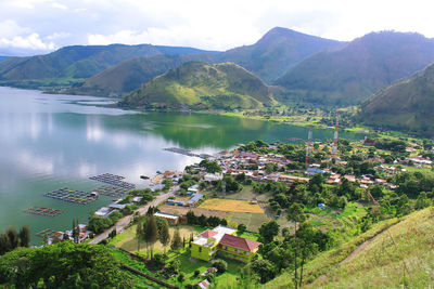 High angle view of trees and buildings by mountains against sky