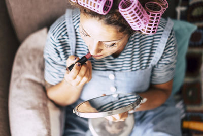 High angle view of woman applying lipstick