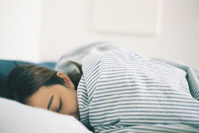 Close-up of woman sitting on bed at home