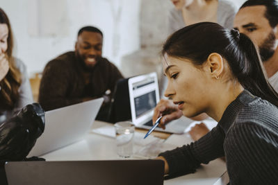 Young female entrepreneur discussing with male and female colleagues in office