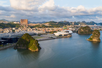 Aerial view of townscape by river against sky