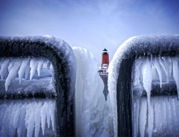 Close-up of frozen railing against lighthouse