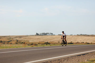 Man riding bicycle on road against sky