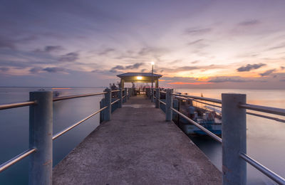 Pier amidst sea against sky during sunset