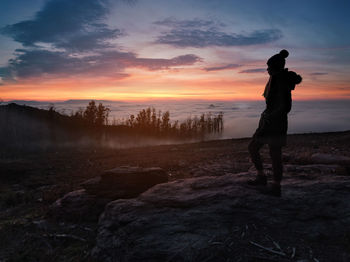 Woman standing on mountain against sky during sunset