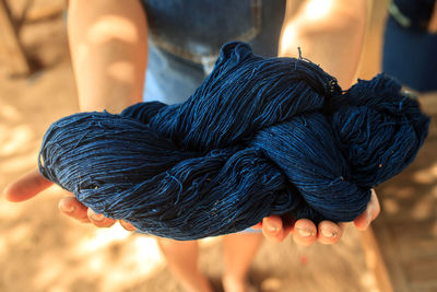 Midsection of person holding dyed thread