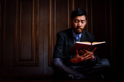 Young man sitting on book