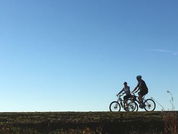 Bicycle on field against clear blue sky