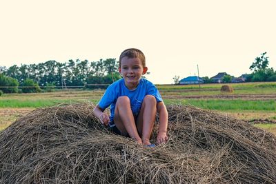 Portrait of smiling boy on field against sky